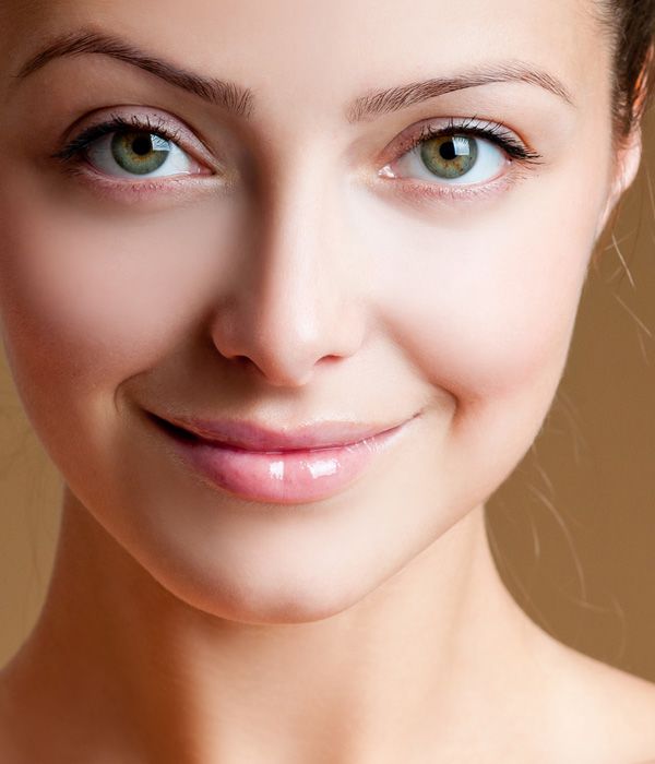 Close up of a woman looking at camera over her bare shoulder, displaying pretty facial contours